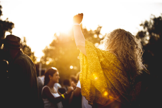 Woman with blonde curly hair dancing at sunset.