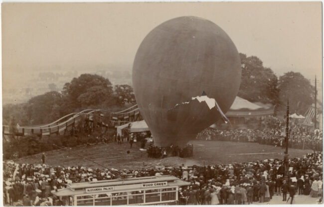 Vintage image in black and white of a large group of people looking at a hot air balloon being inflated.