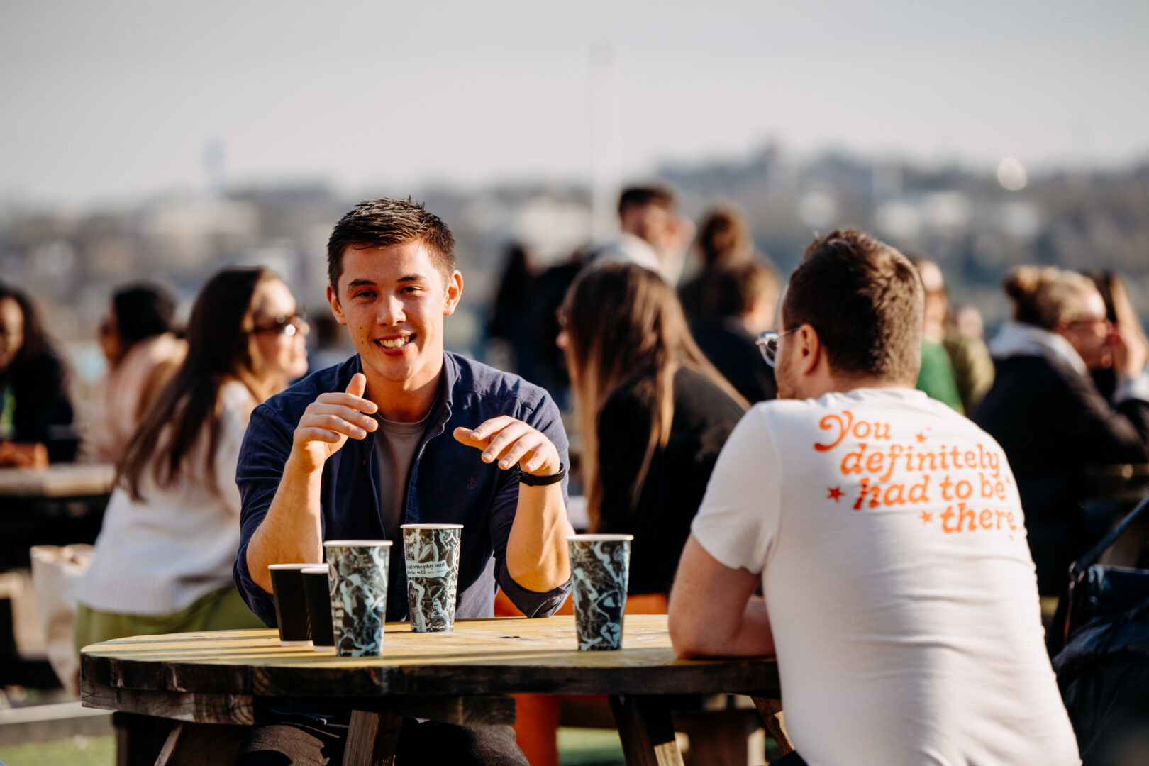 People sat at a table outside enjoying a drink in the sun.