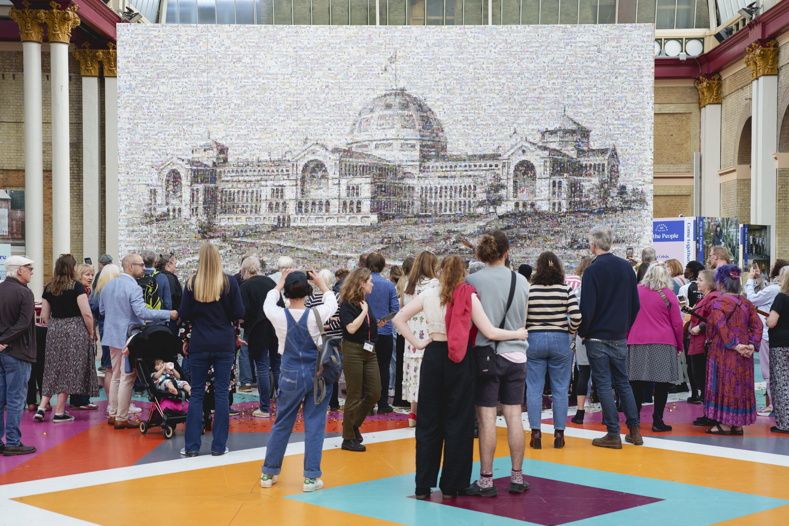 Group of people stood in front of historic illustration of Alexandra Palace