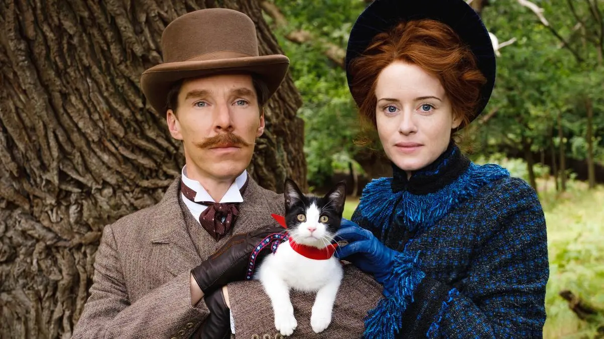 A press shot from the show 'The Electrical Life of Louis Wain' featuring Benedict Cumberbatch and Claire Foy. They are posing proudly in victorian dress whilst holding a black and white kitten.
